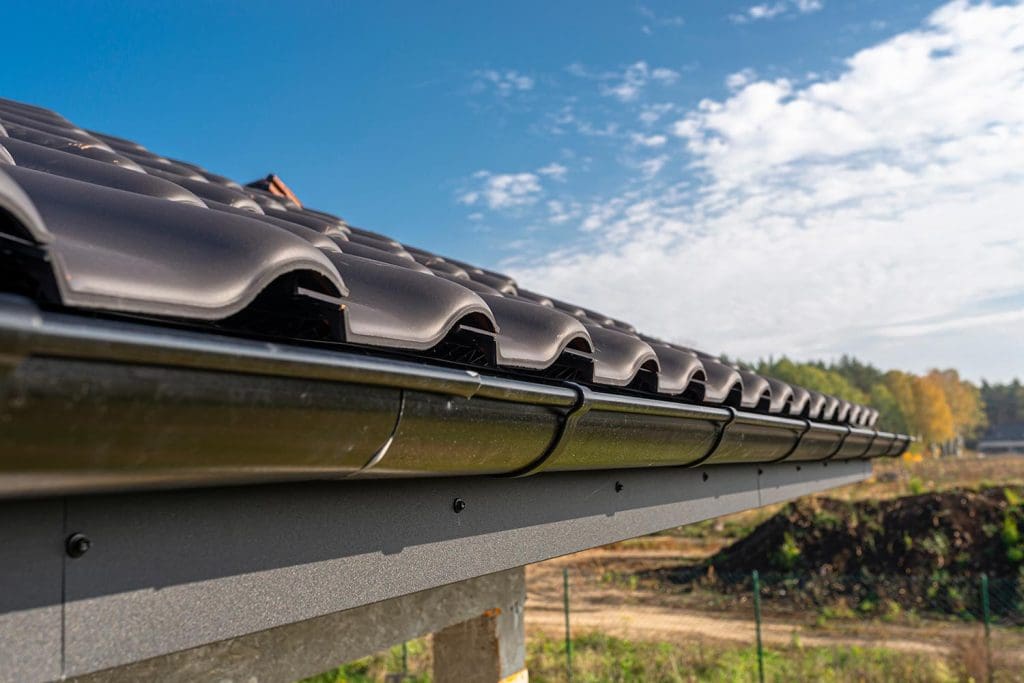 A metal black gutter on a roof covered